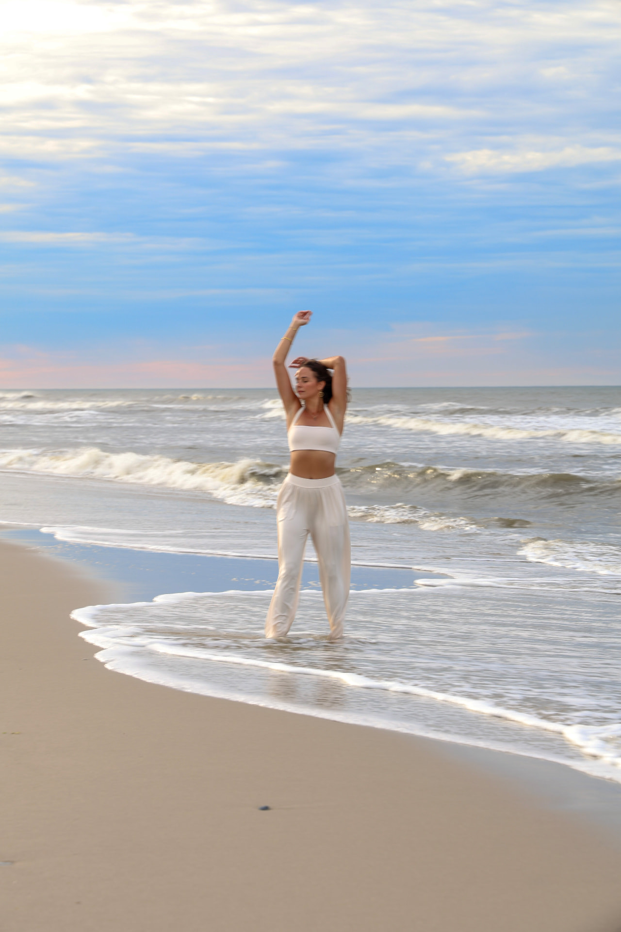A woman moving on the shoreline with her arms raised